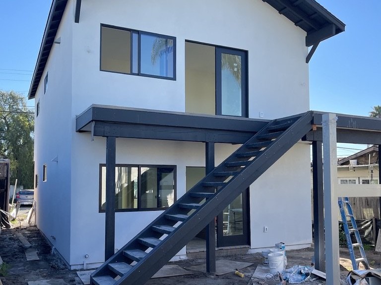 Two-story ADU near completion white stucco exterior dark trim staircase San Diego - Complete Builders Inc