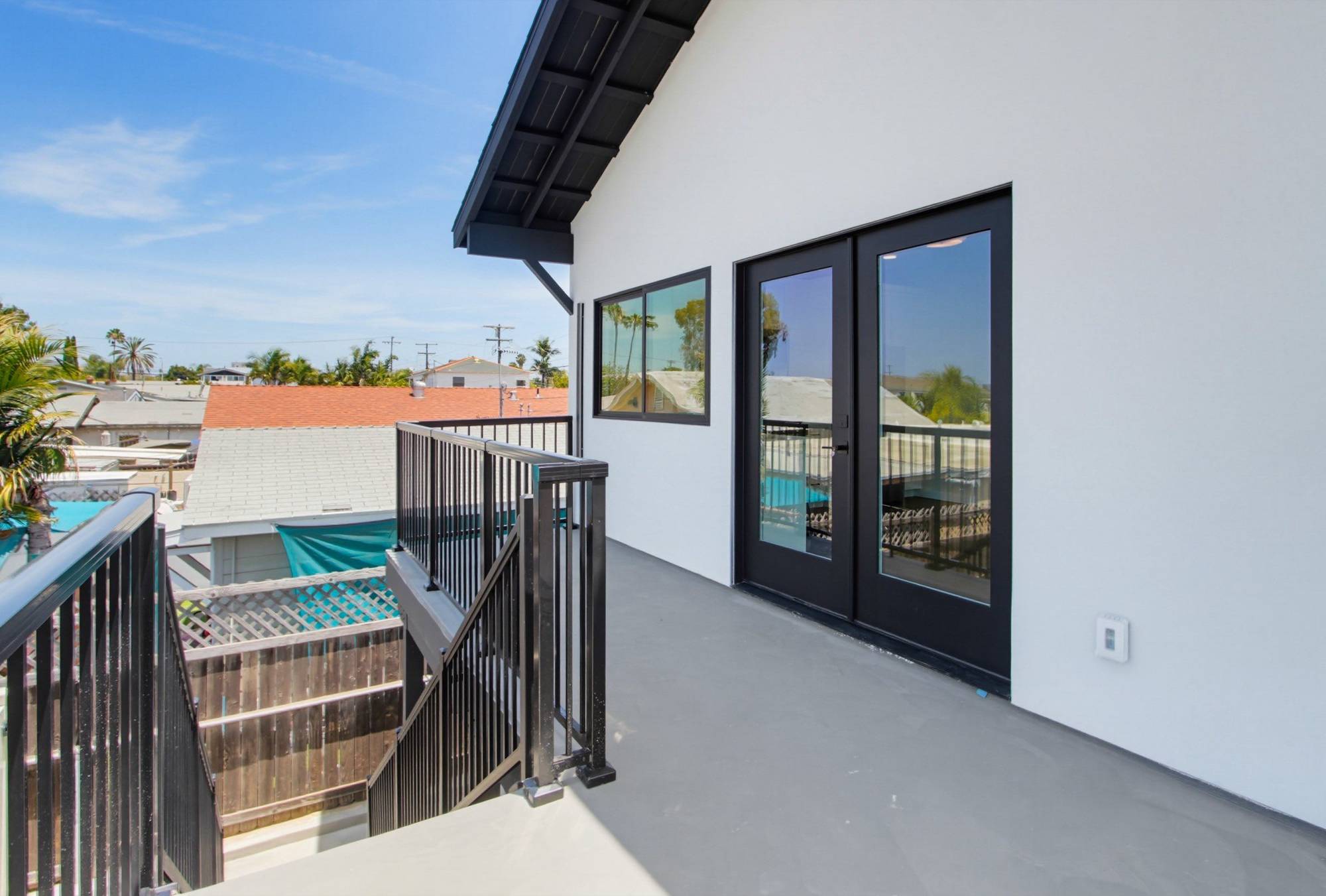 Two-story ADU private deck with black metal railing, San Diego
