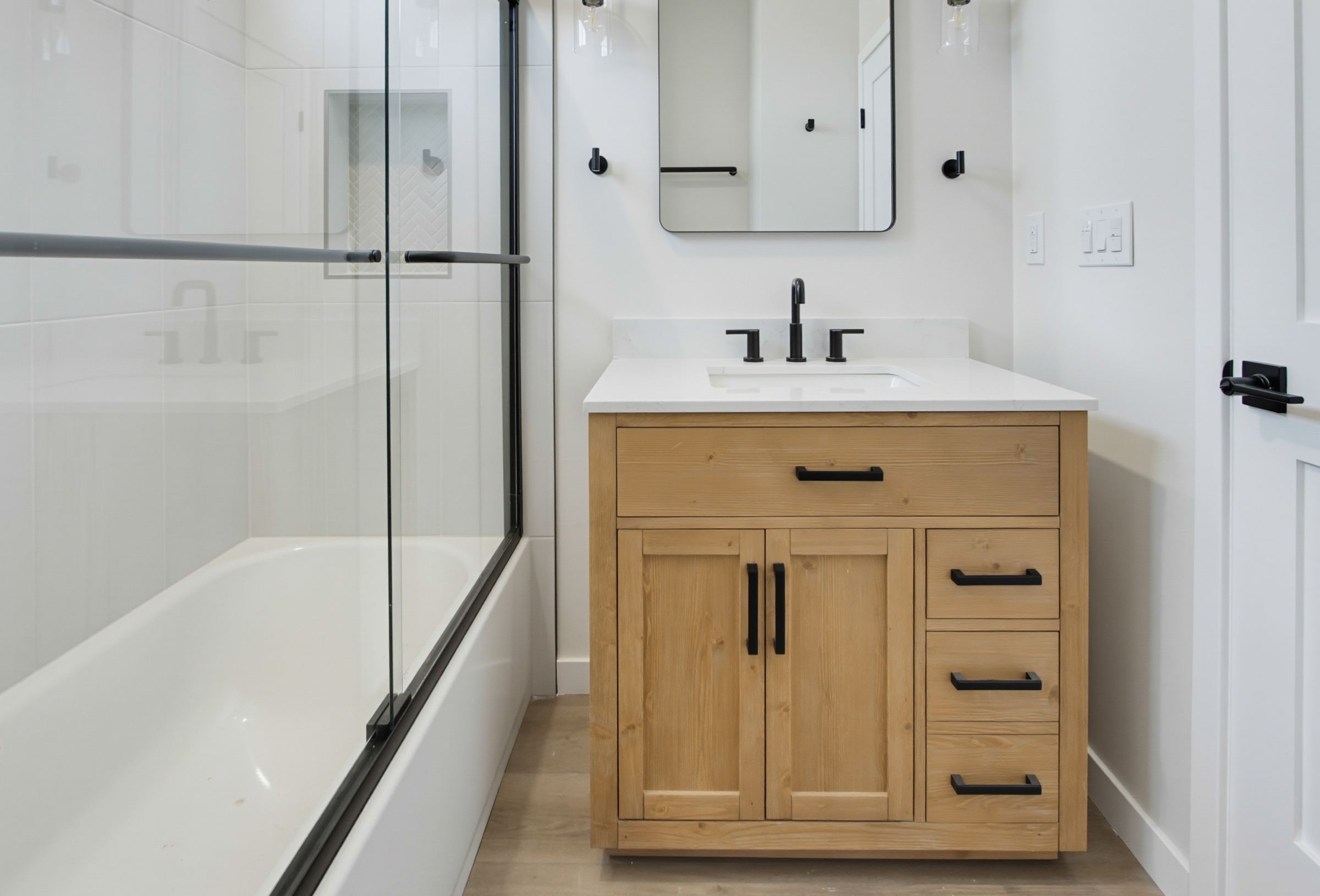 Two-story ADU bathroom with wood vanity and black fixtures, San Diego