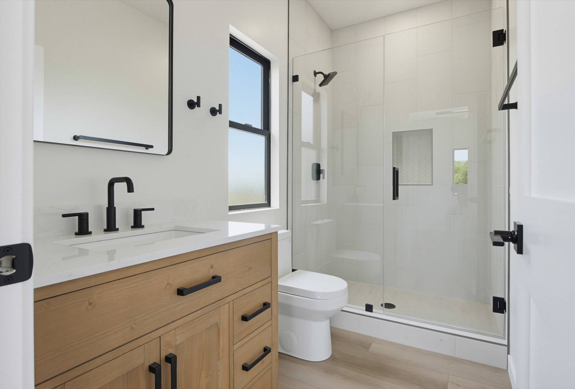 Two-story ADU bathroom with glass shower and black fixtures, San Diego