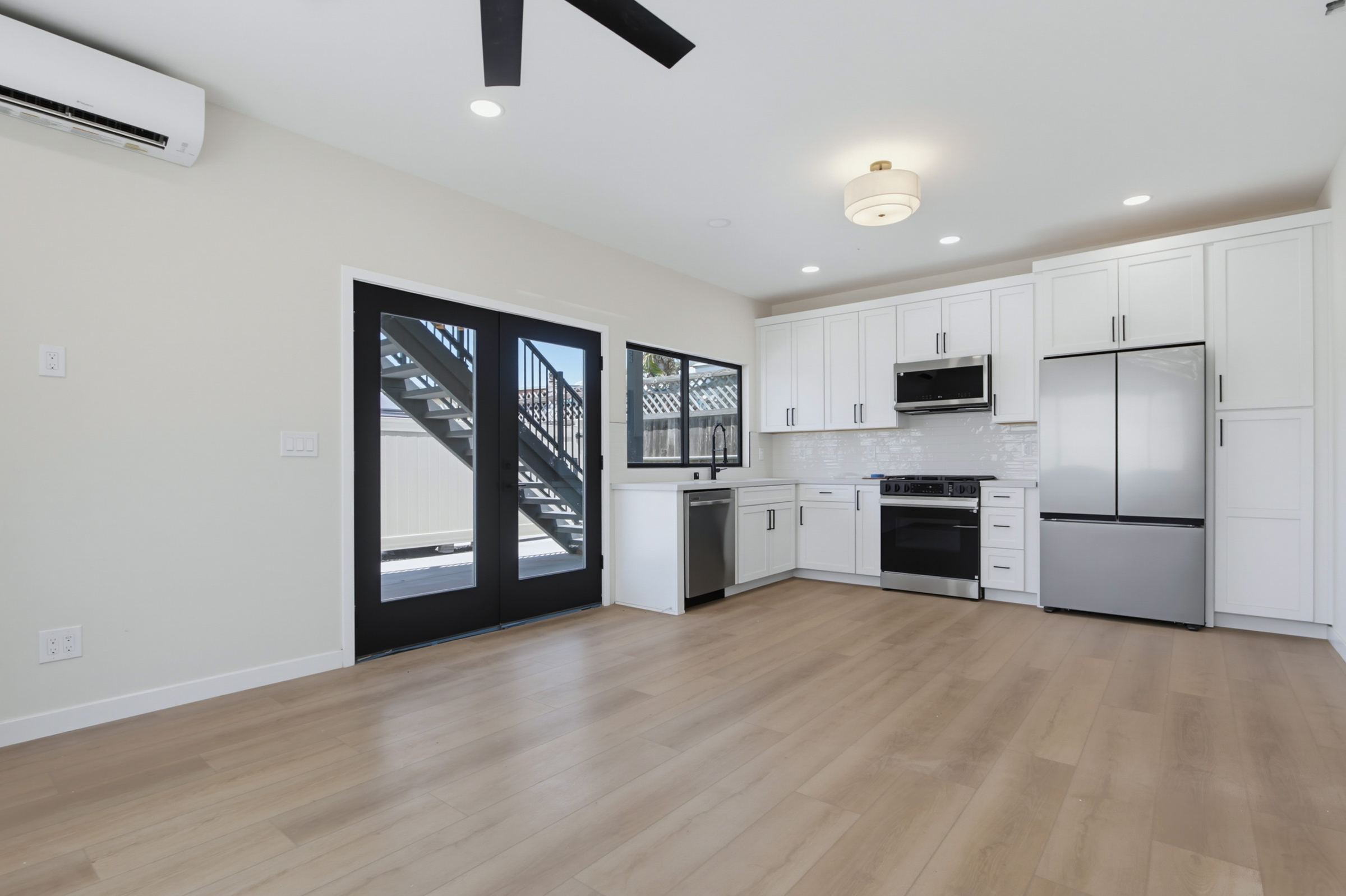 Two-story ADU open kitchen and living area with black french doors, San Diego