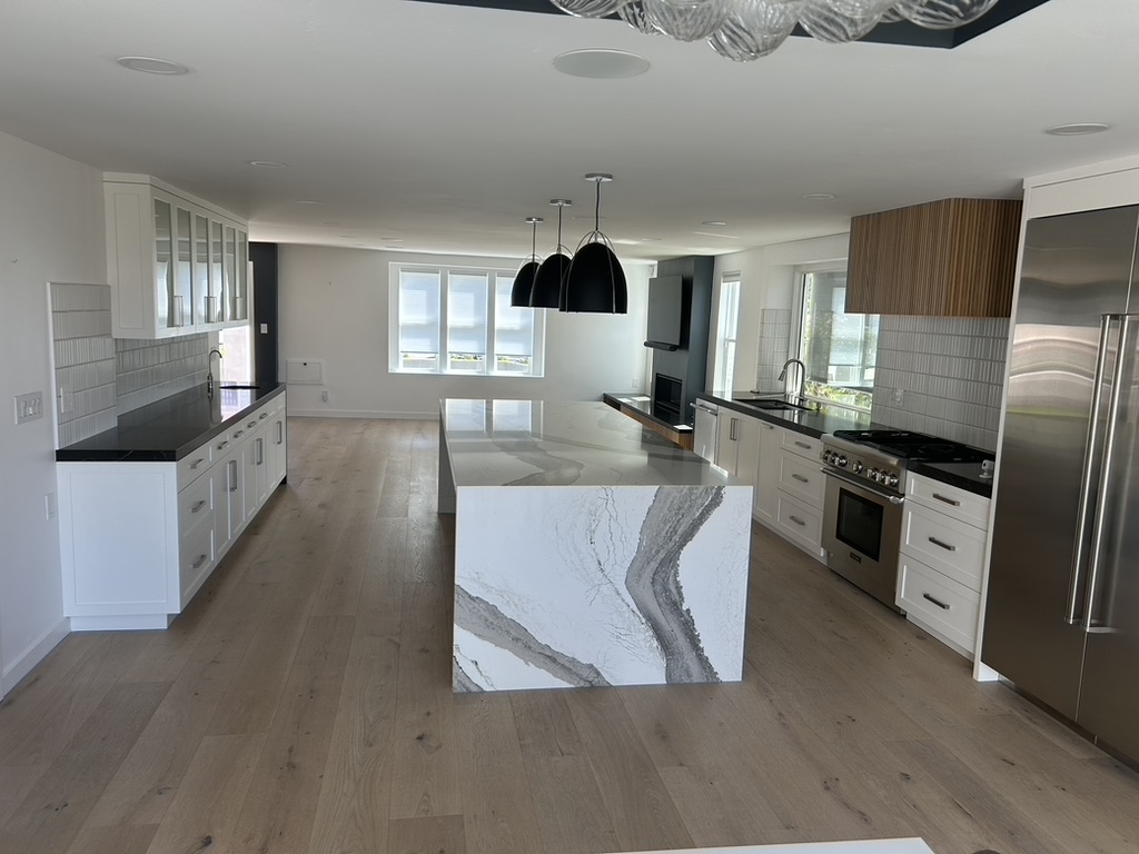 Large kitchen remodel marble waterfall island black pendants San Diego - Complete Builders Inc