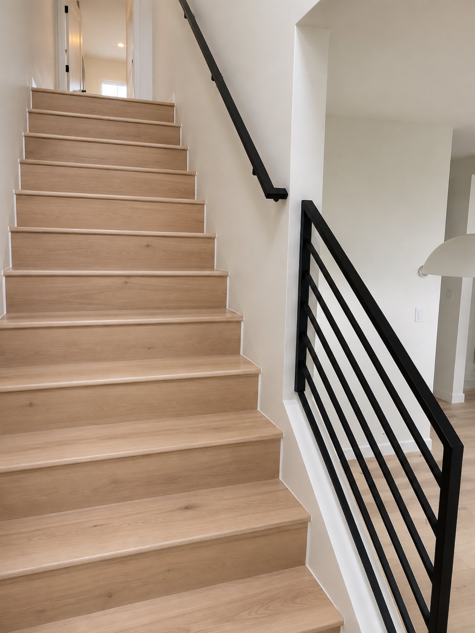Finished interior staircase black metal railing white oak treads San Diego - Complete Builders Inc
